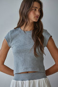 Woman wearing a gray crop top against a plain background