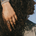 woman wearing Gold ring with a central blue gemstone 