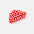 Red and white checkered hair comb on a light gray background