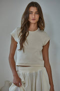 Woman wearing a white outfit against a plain background