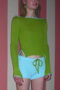 Woman wearing green sweater and bue shorts