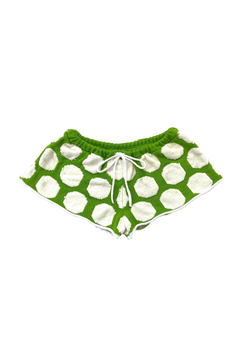 Green shorts with white polka dots on a white background