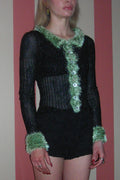 Person wearing a black outfit with green trim against a plain background