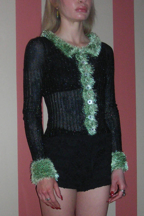 Person wearing a black outfit with green trim against a plain background